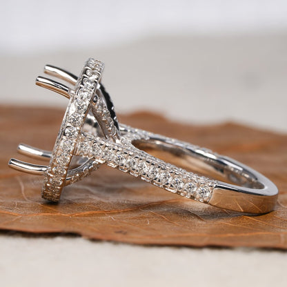Engagement ring with white metal oval halo setting, pavé band, open four-prong center setting, angled side view
