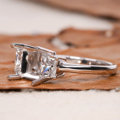 Engagement ring with white metal band, rectangular side stones, open center setting, four-prong design, side profile view
