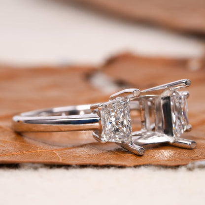 Engagement ring with white metal band, rectangular side stones, open center setting, four-prong design, angled side view
