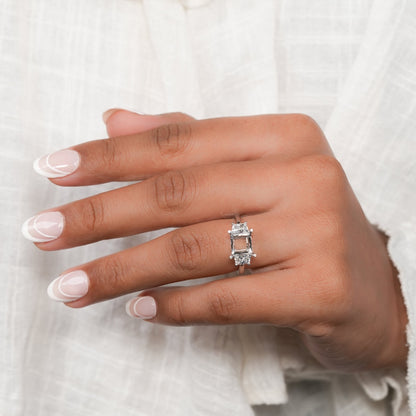 Engagement ring with white metal band, rectangular open center setting, tapered side stones, worn on hand, top view
