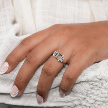 Engagement ring with white metal band, rectangular open center setting, tapered side stones, worn on hand, top angled view
