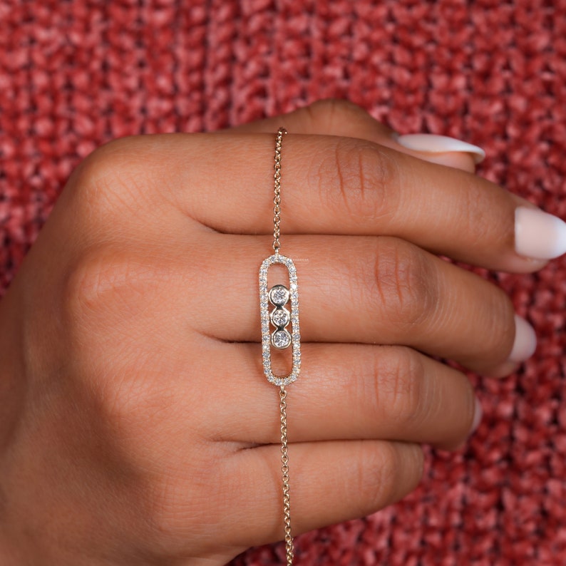 Bracelet with yellow metal chain, oval pavé-set link centerpiece and three round bezel-set stones, shown worn on hand, top view
