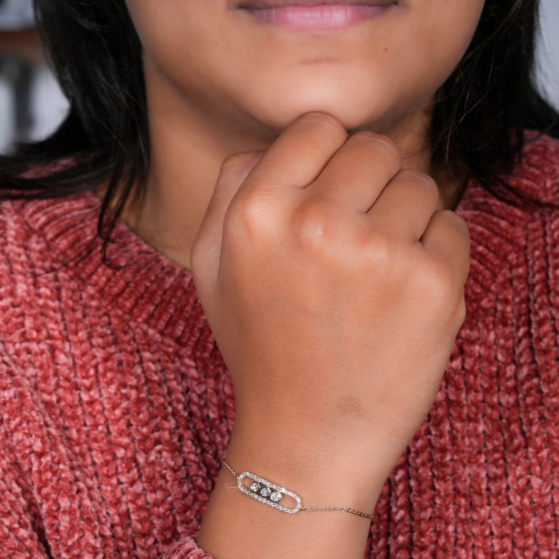 Bracelet with yellow metal chain, oval pavé-set link centerpiece and three round bezel-set stones, worn on wrist, front view
