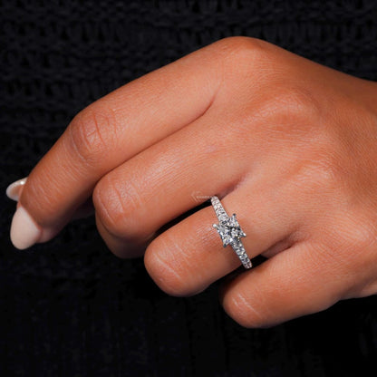 Engagement ring with white metal band, square center stone, pavé band and four-prong setting, worn on finger at angled view
