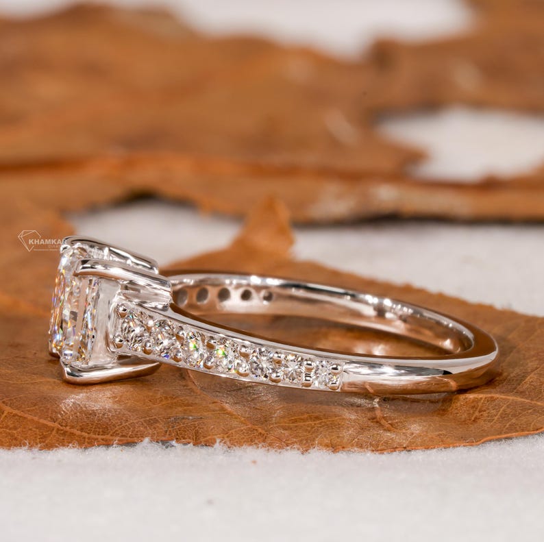 Engagement ring with white metal band, square center stone, pavé shoulders and raised four-prong setting, side profile view
