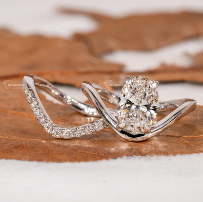 Engagement ring set with oval solitaire diamond and curved pavé wedding band in white metal, angled front view