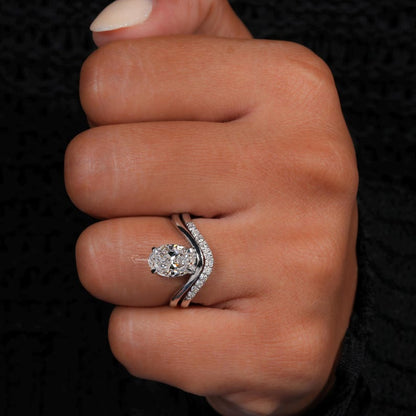 Engagement ring with oval cut clear center stone, silver tone split bypass band with pavé accents, worn on hand, front view