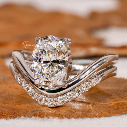 Engagement ring set with oval solitaire diamond and curved pavé wedding band in white metal, close-up front angle view