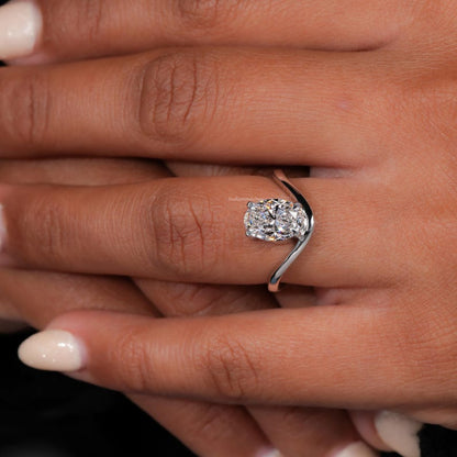 Engagement ring with oval cut clear center stone, silver tone curved solitaire band, worn on hand, angled top view