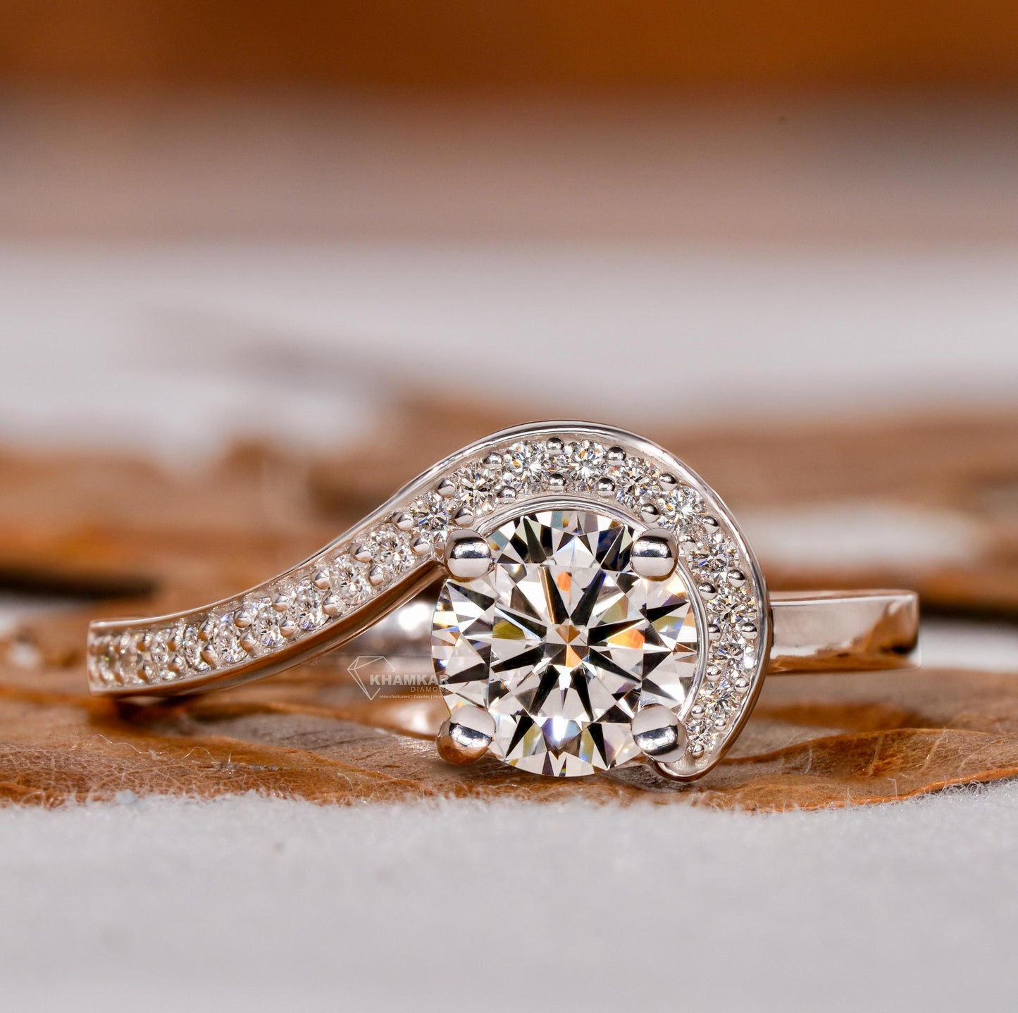 Engagement ring with round center stone, white metal swirl design, pavé accent band, front view
