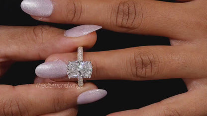 Engagement ring with two cushion-cut clear gemstones, polished yellow metal pavé band, four-prong setting, worn on finger, front view
