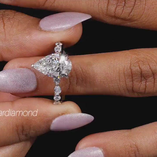 Engagement ring with polished white metal band, heart-shaped clear gemstone and round accent stones, front view on finger
