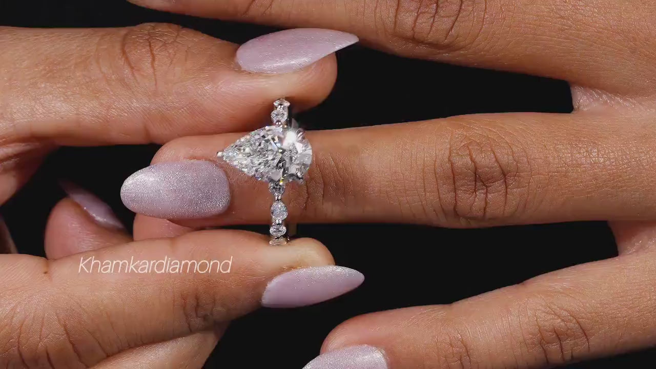 Engagement ring with polished white metal band, heart-shaped clear gemstone and round accent stones, front view on finger
