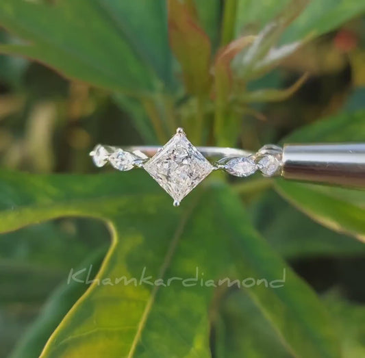 Engagement ring with white metal twisted band, princess-cut center stone, marquise side stones, close-up video frame against green background
