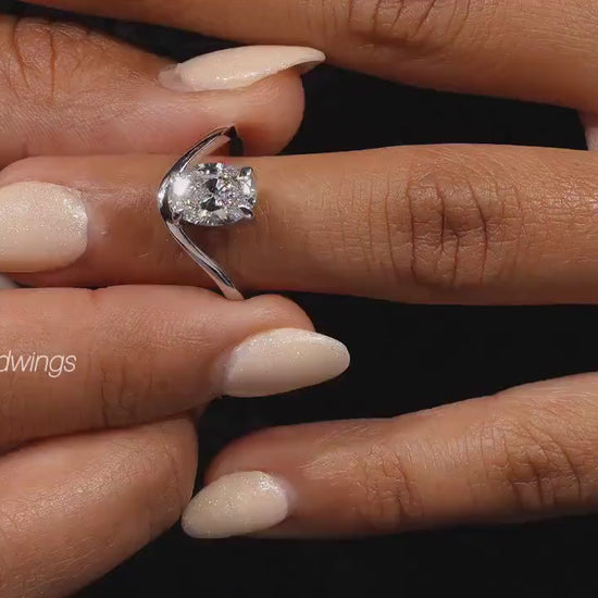 Engagement ring with oval cut clear center stone, silver tone curved solitaire band, worn on hand, close-up video frame