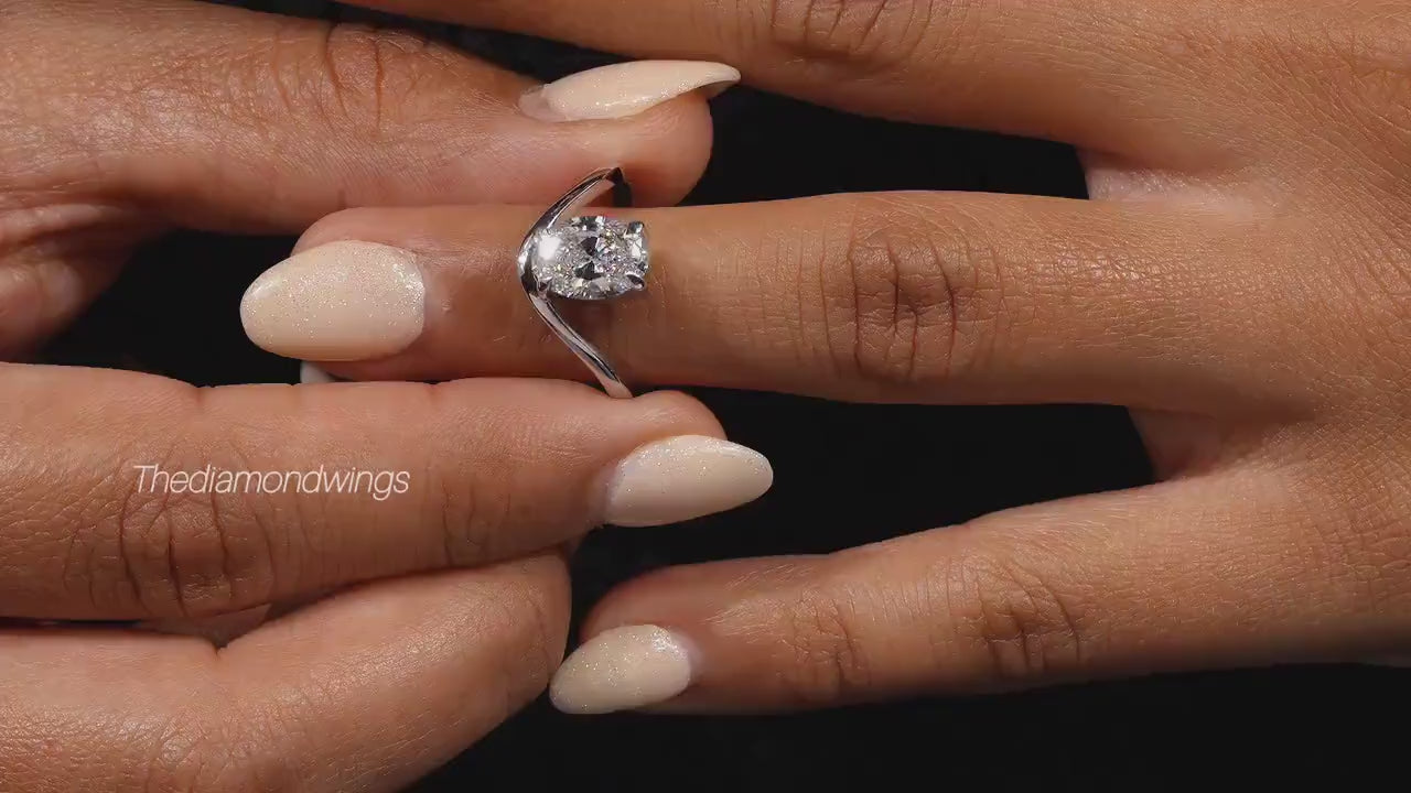Engagement ring with oval cut clear center stone, silver tone curved solitaire band, worn on hand, close-up video frame