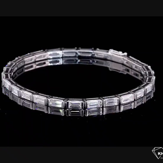 Bracelet with white metal links, rectangular step-cut stones in tennis bracelet design, top angled view on a black background
