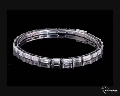 Bracelet with white metal links, rectangular step-cut stones in tennis bracelet design, top angled view on a black background

