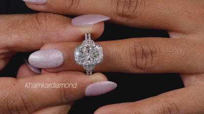 Engagement ring with white metal split shank, elongated cushion-cut clear center stone, halo setting, worn on finger, front view
