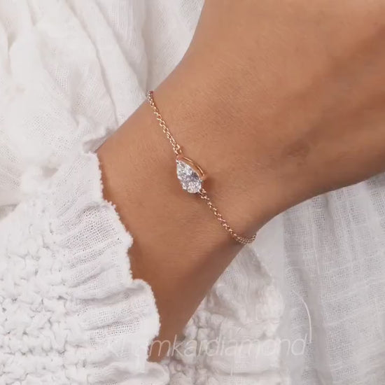 Bracelet with pear-shaped clear stone on yellow metal chain, worn on wrist, close-up lifestyle view, bracelet jewelry video frame
