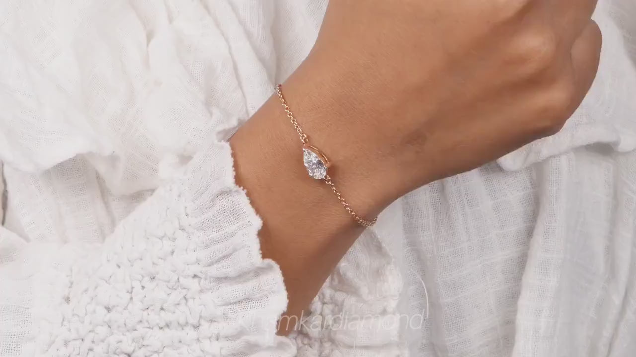 Bracelet with pear-shaped clear stone on yellow metal chain, worn on wrist, close-up lifestyle view, bracelet jewelry video frame
