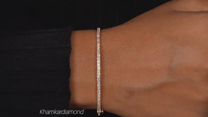 Bracelet with yellow metal band, round stones in a slim tennis bracelet design, worn on a wrist, close-up top view
