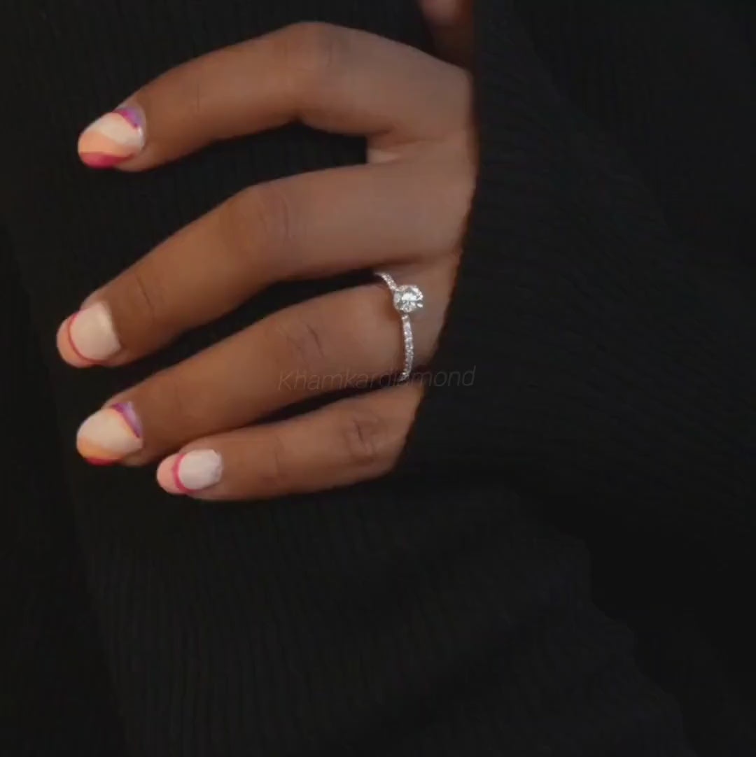 Engagement ring with round clear center stone, white metal pavé band, worn on hand, front view
