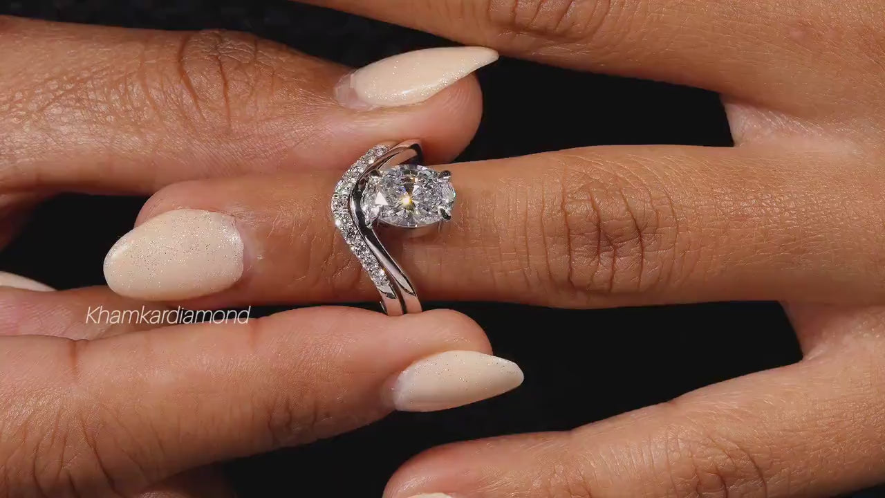 Engagement ring set with oval solitaire diamond and curved pavé wedding band worn on a hand, close-up view